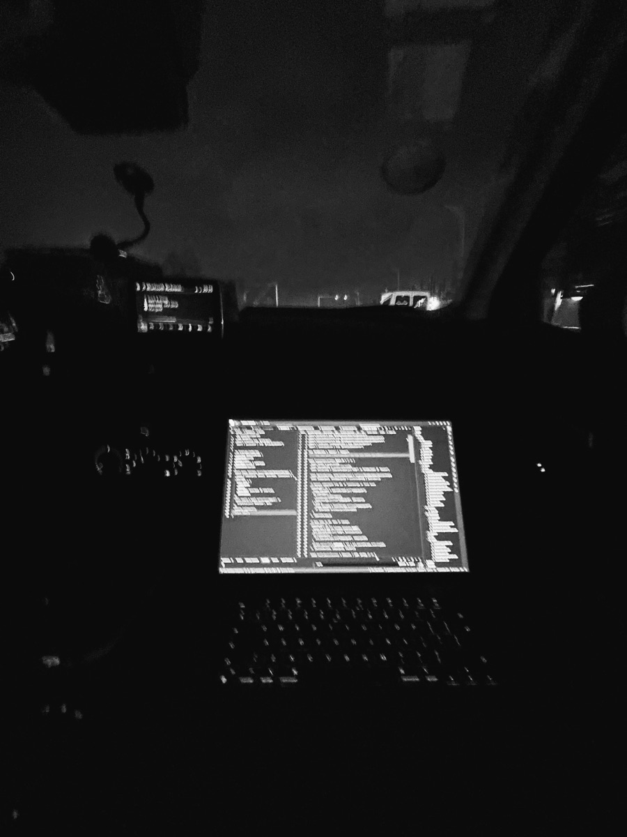 A laptop open to code during a late car ride.
