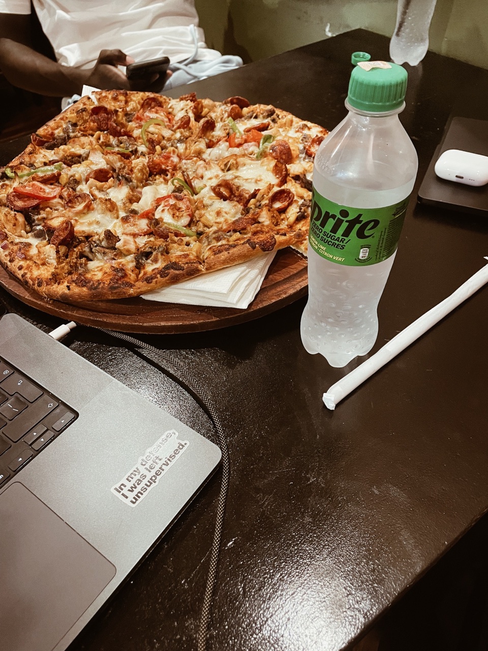 Pizza, a laptop, and a drink gathered around a table.